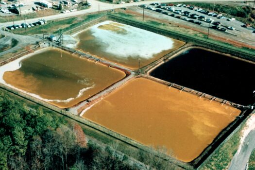 Aerial photo displaying four square ponds of brown and green water.